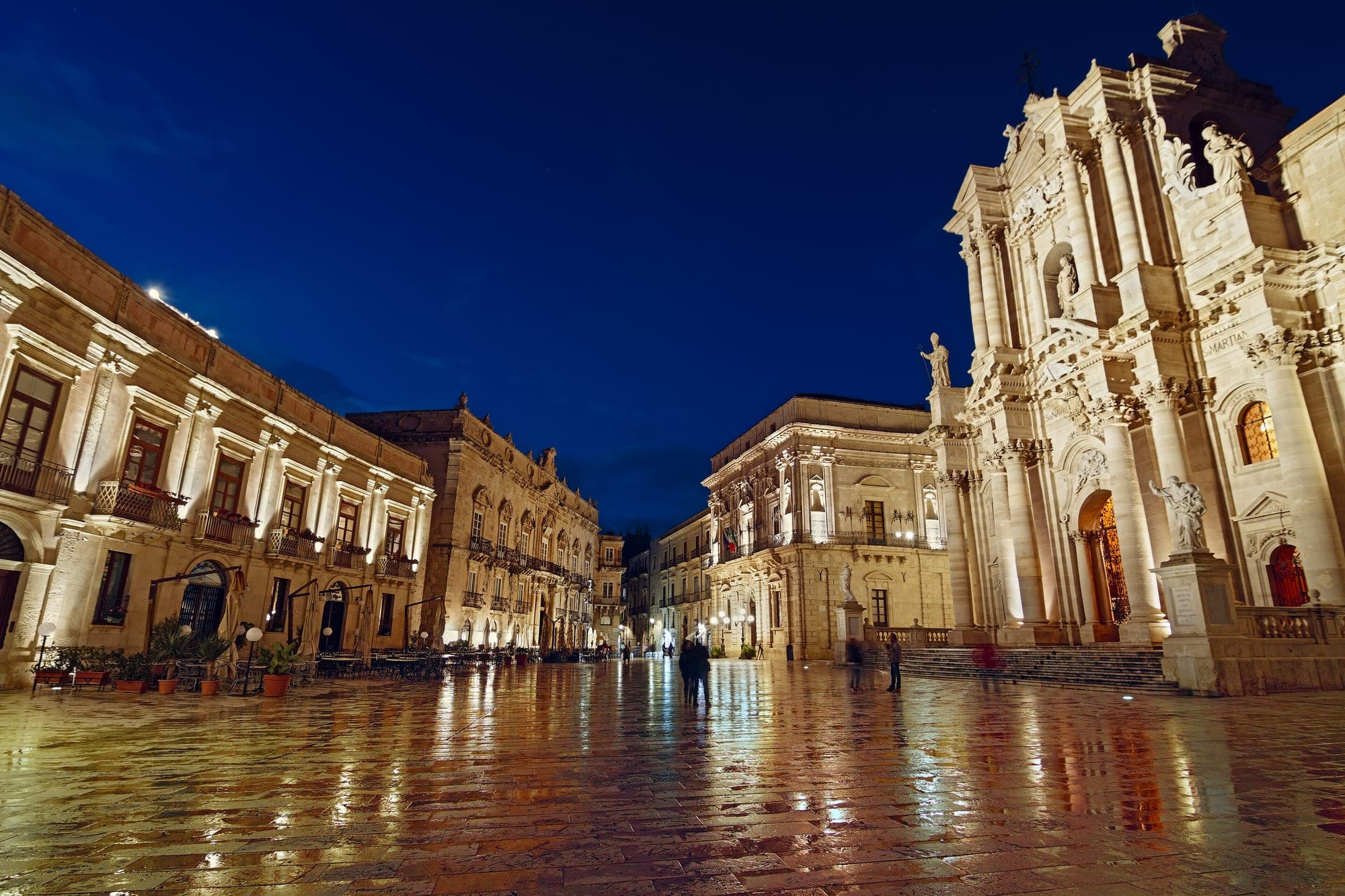 Piazza Duomo in Ortigia at blue hour, the baroque cathedral front lit and the stone paving reflecting it
