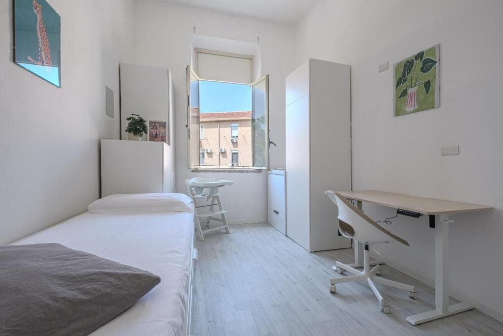 The second bedroom with a single bed, a desk and a window over the neighbourhood rooftops