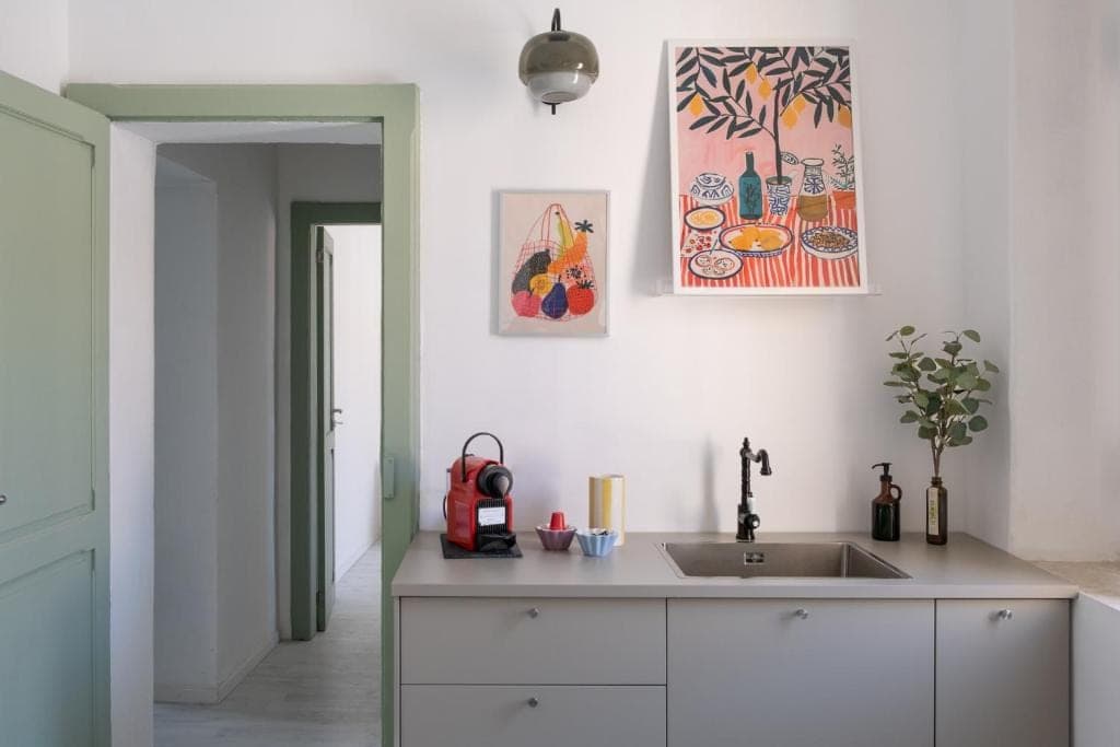 The kitchen run in pale grey, with the red coffee machine and prints on the wall