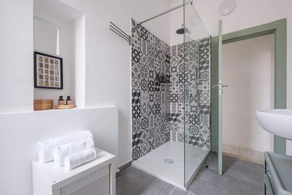 The shower tiled in black and white cement tiles, with folded towels